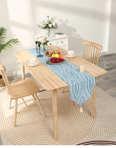 Detail of blue and white geometric table runner with tassels on a wooden dining table