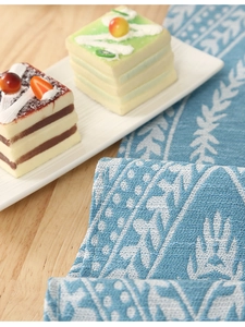 Detail of blue and white chenille table runner with leaf jacquard on wooden table