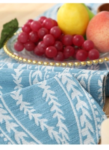 Detail of blue jacquard table runner featuring woven botanical patterns and cotton texture