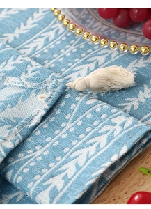 Detailed view of blue and white geometric table runner with cotton tassel fringe