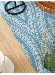 Macro detail of blue and white geometric linen table runner on light wooden surface