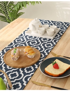 Detailed view of dark blue geometric table runner with white clover pattern on wood table
