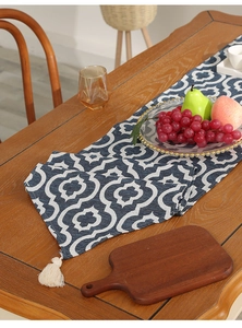 Close-up of blue and white Moroccan pattern table runner with creamy white tassels