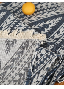 Detail of woven table runner featuring navy blue geometric leaf patterns and white tassels