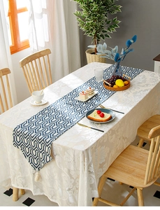 Detail of blue geometric linen table runner with fringes on a textured tablecloth