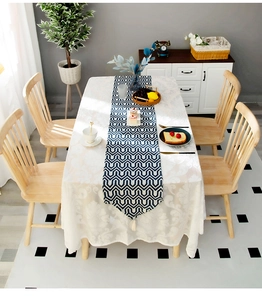Detail of white damascus patterned tablecloth and navy geometric runner with tassels