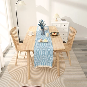 Nordic light blue table runner with geometric leaf pattern and white tassels on wood table