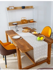 Detail of beige cotton linen table runner with geometric patterns and fringe on wooden table
