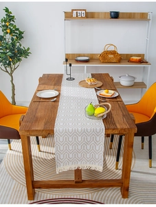 Close-up of geometric pattern table runner with fringe tassels on a wooden dining table