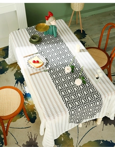 Detail of white lace tablecloth with geometric wave table runner and fringe tassels