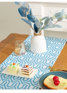 Close-up of modern table runner with blue and white geometric wave patterns in cotton linen