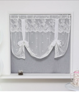 Close-up of white lace curtain with floral embroidery and decorative ribbon bows