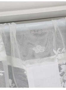 Close-up of white lace curtain fabric showing detailed floral jacquard patterns