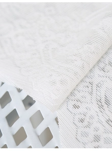Macro detail of white lace curtain fabric with intricate floral geometric patterns