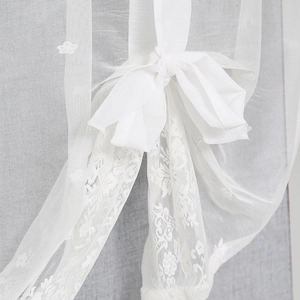 White semi-transparent lace curtain with floral embroidery and decorative bow ties