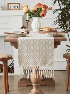 Detailed close-up of woven geometric pattern and long tassels on cotton linen table runner