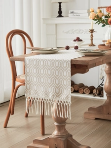 Close-up of beige geometric jacquard table runner with handmade woven fringe tassels