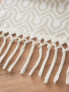 Detail of woven table runner featuring geometric wave patterns and handcrafted tassels