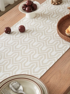 Close-up of geometric jacquard table runner with textured woven fabric on wooden table