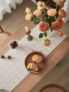 Close-up of jacquard table runner with geometric pattern on a wooden dining table