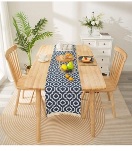 Detail of blue bohemian table runner with white geometric patterns and cream cotton tassels