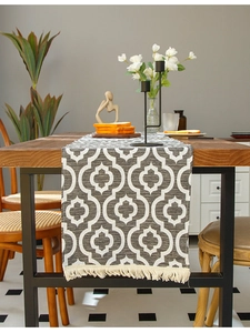 Detail of grey Moroccan geometric table runner featuring handmade woven tassels on wood