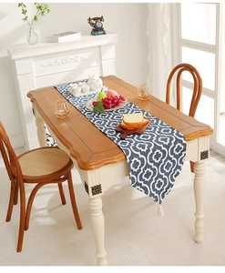 Close-up of navy blue table runner with white Moroccan pattern and fringe tassels