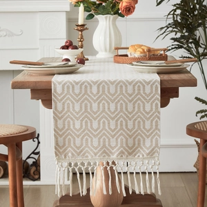 Modern geometric jacquard table runner with decorative tassels on dark wood table