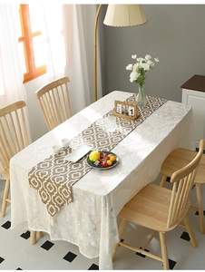 Detail of coffee brown checkered table runner with tassels and cream jacquard tablecloth