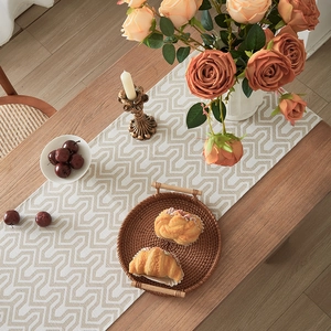 Modern jacquard table runner with geometric zigzag patterns on a natural wood table