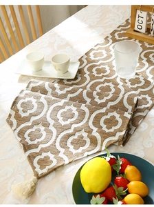 Modern geometric table runner with tassels and woven texture shown in a cozy dining setting