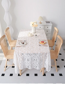 Detail of white lace tablecloth featuring delicate floral hollow embroidery and scallop edges