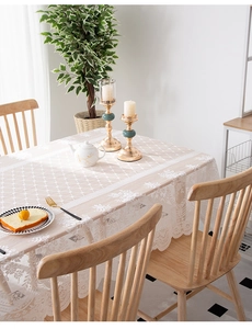 Detail of light apricot lace tablecloth with diamond grid pattern and floral embroidery