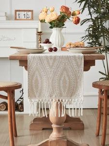 Dettaglio di runner da tavola kaki con trama geometrica e nappe in cotone morbido