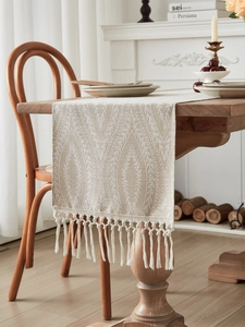 Dettaglio del runner da tavola in lino beige con motivi geometrici e bordi a nappe