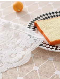 Close-up of white lace fabric with intricate floral crochet patterns and hemmed edges