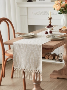 Dettaglio del runner da tavola boho beige con trama geometrica e nappe decorative
