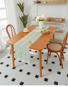 Close-up of light green table runner with geometric lines and tassel fringe detail