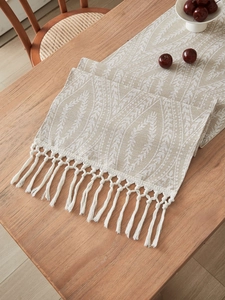 Dettaglio del runner da tavolo in cotone e lino con nappe e motivi a piuma boho