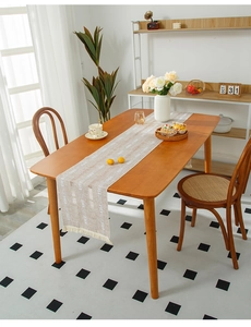 Detail of beige linen table runner with white geometric patterns and tassel edges