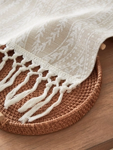 Dettaglio del runner da tavola boho in lino con trame fitte e nappe fatte a mano