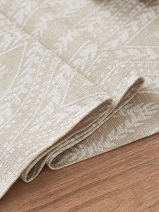 Dettaglio di un runner da tavola in cotone e lino beige con motivi geometrici bianchi