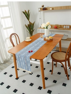 Detail of blue woven table runner with white geometric patterns and tassel edges