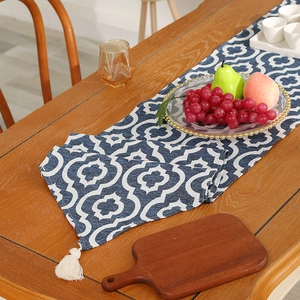 Modern navy blue table runner with white quatrefoil patterns and elegant white tassels
