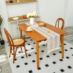 Linen table runner with woven geometric patterns and white tassels on a wooden dining table