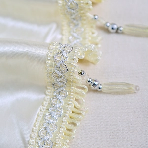 Luxuriöse cremefarbene Gardine mit eleganten Silberperlen-Quasten und Wellenspitze
