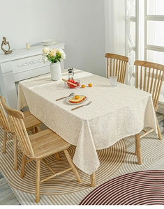 Detailed view of beige rectangle tablecloth with fine white speckled texture and drape
