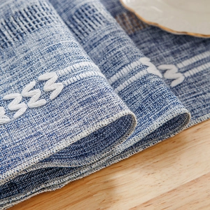 Blue and white woven table runner with tassel texture on a light wooden table surface