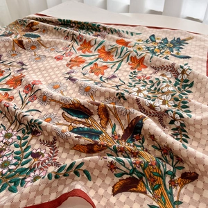 Detailed close-up of checkered silk scarf with floral prints and red borders