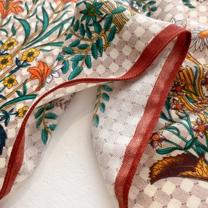 Detail of silk scarf showing floral print with checkerboard pattern and hand-rolled edges